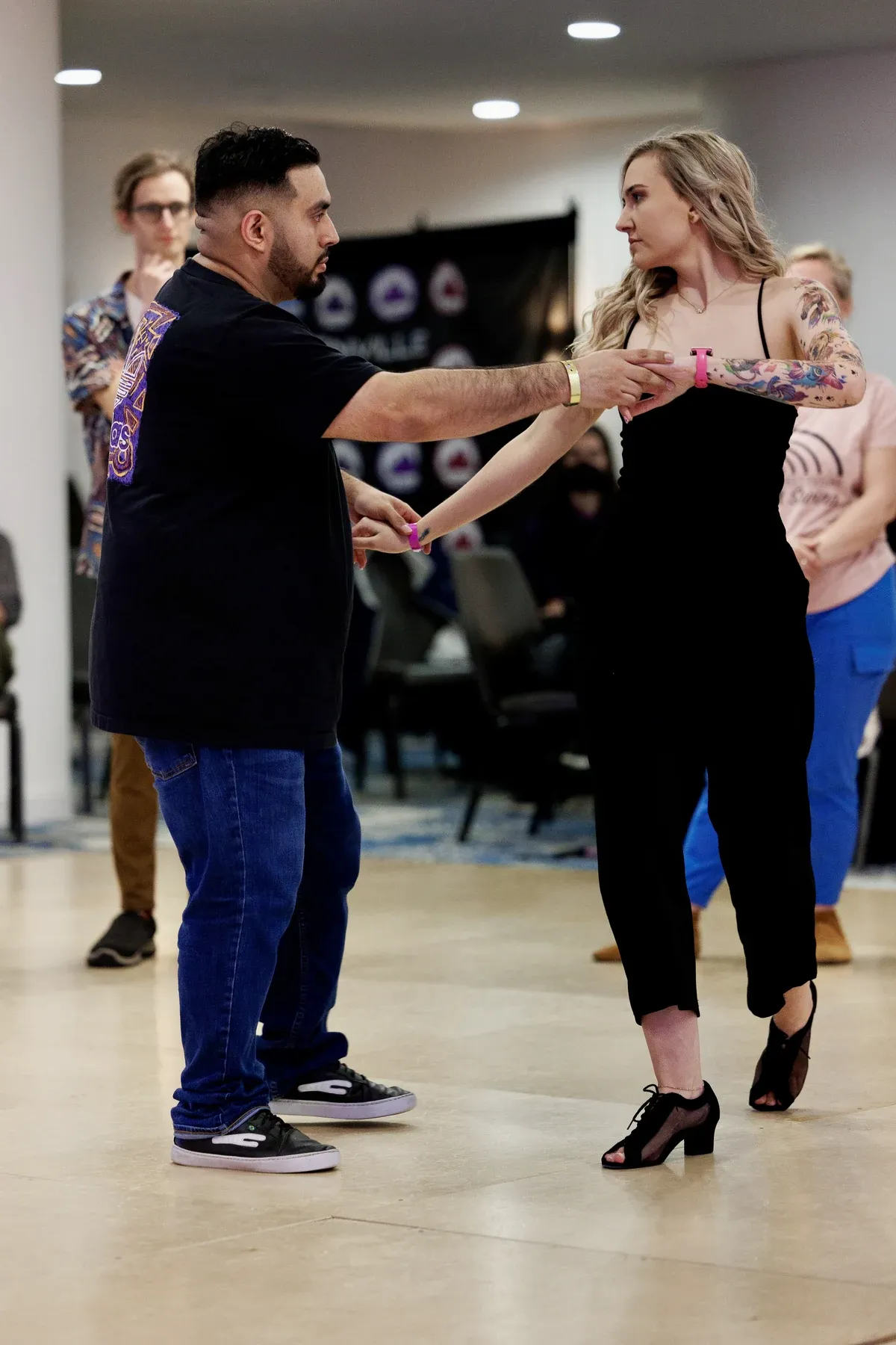 Kière and a dance partner holding hands during a class, with other dancers behind them.