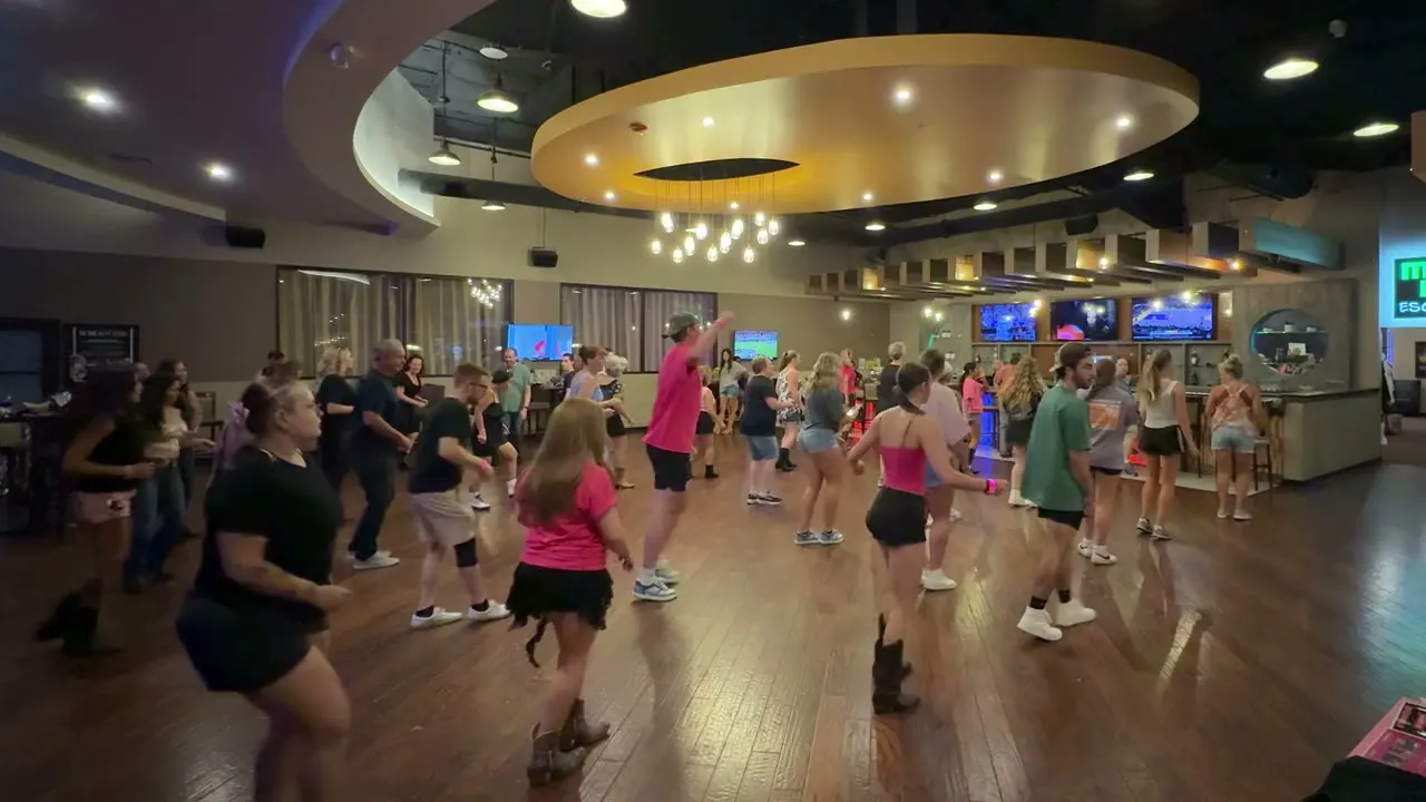 A full floor of dancers mid-line-dance during a real recurring Rhinestone dance night at Spare Time Greenville.