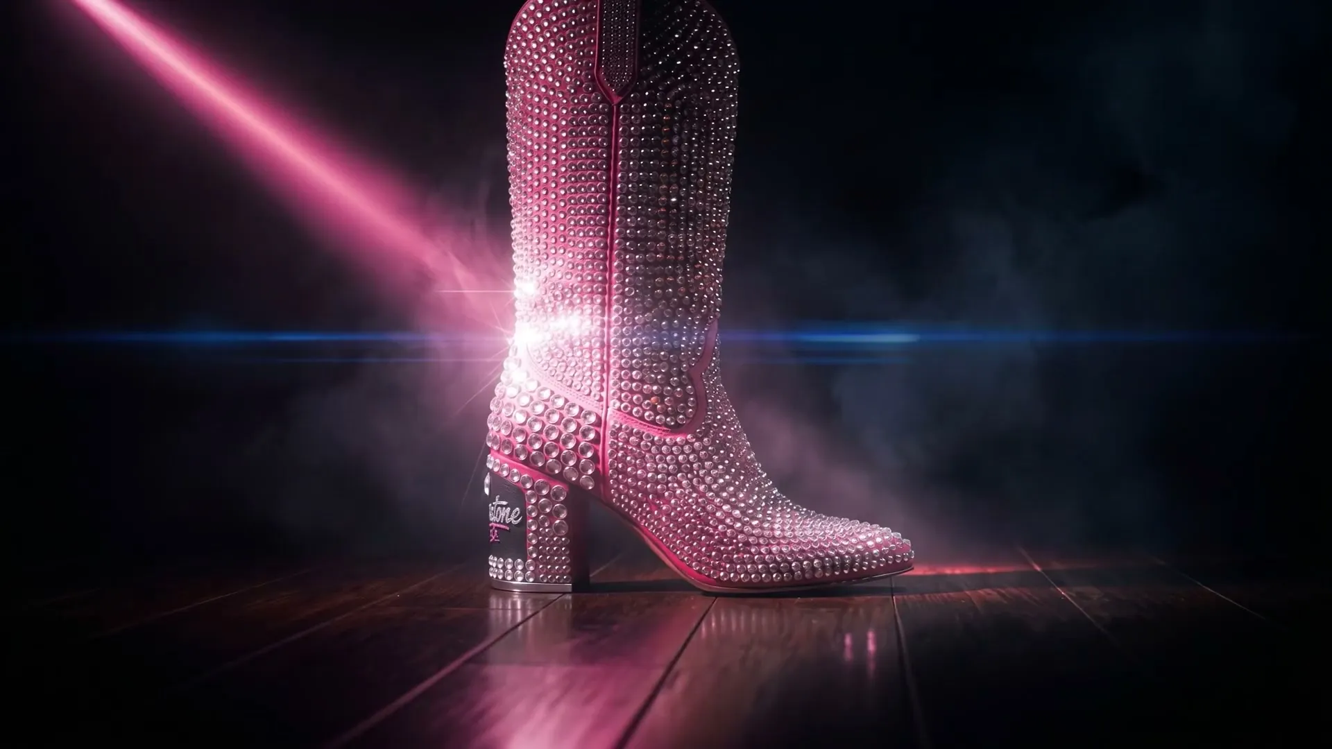 A slow orbit around a crystal-pavé cowboy boot under a hot-pink beam in a dark haze.
